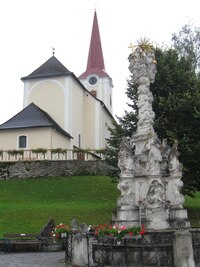 Jsme v Rakousku u kostela s mariánským sloupem v popředí