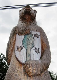 s méďou a znakem obce opodál