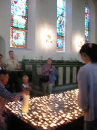 a lidé zapalují obětem atentátu svíčky