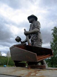 Dole u řeky je symbolická socha zlatokopa