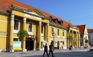 Vedle stojí palác s antickým sloupovím...